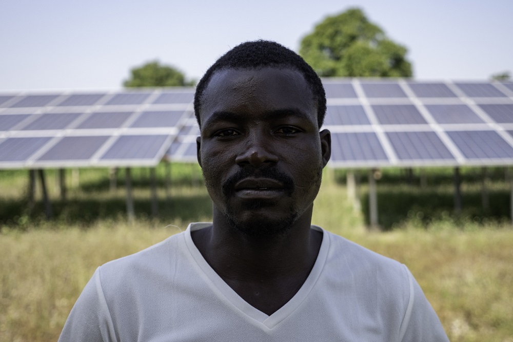Un ingeniero de mini-grid se encuentra frente a la mini-grid de la comunidad en Bisanti, Nigeria. Foto: Geraint Hill, 2018